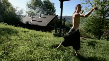 Uzun menzilli bir adamın yangın gösterisi için uzun çekim sabah eğitimi. Yeşil bir ormanın yanında açık havada güneşli bir yaz sabahı meşaleler ve zincirler ile ateş olmadan bir performans için hazırlık.