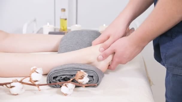 Close-up of a male physiotherapist doing foot massage to a young girl in a beauty and health spa. Foot and body care concept — Stock Video