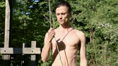 Bir yangın gösterisi için uzun saçlı bir adamın orta yakın çekim sabah eğitimi. Açık havada güneşli bir yaz sabahı meşaleler ve zincirler ile ateş olmadan bir performans için hazırlık