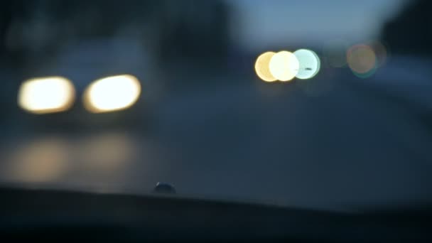 Abstract background blurred view of the lights of oncoming cars on a country road at dusk or in the early morning. Low key defocus bokeh of headlights from POV — Stock Video