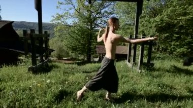 Uzun menzilli bir adamın yangın gösterisi için uzun çekim sabah eğitimi. Yeşil bir ormanın yanında açık havada güneşli bir yaz sabahı meşaleler ve zincirler ile ateş olmadan bir performans için hazırlık.