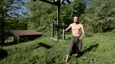 Uzun menzilli bir adamın yangın gösterisi için uzun çekim sabah eğitimi. Yeşil bir ormanın yanında açık havada güneşli bir yaz sabahı meşaleler ve zincirler ile ateş olmadan bir performans için hazırlık.