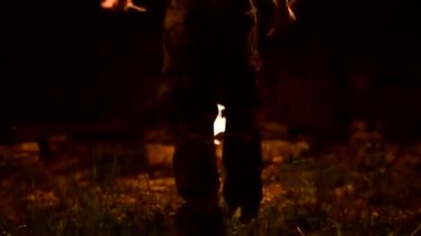 Ateş gösterisi. Adam yanan iki meşaleyle hokkabazlık yapıyor. Gece şovu. Fakirin ustalığı. Close