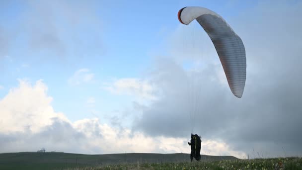 Ein männlicher Gleitschirmflieger hebt vor der Abendwolkenkulisse in einem Outdor einen Flügel, kann aber nicht fliegen. Fehlschlag beim Versuch abzuheben — Stockvideo