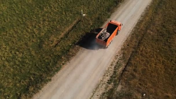 トラックの航空写真。トラックの中で建設破片の石や砂を輸送するダンプトラックは、田舎道に沿って乗ります。トラック輸送物流貨物配送 — ストック動画