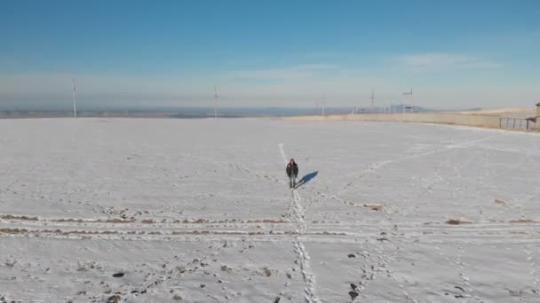 Siguiendo a los hombres en jeans y zapatos calientes caminando en el campo de nieve en un día soleado de invierno. Vista aérea desde arriba — Vídeos de Stock