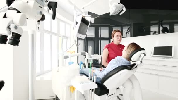 Gözlüklü bir diş hekimi kadın ile istişare genç bir kız bir stamotoloji ofisinde bir sandalyede oturuyor. Doktor ve hastanın konuşma — Stok video