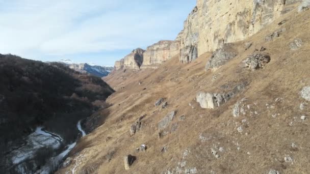 Veduta aerea del movimento lungo la parete rocciosa del canyon nella gola nel Caucaso. Molto vicino alla roccia in inverno quando c'è poca neve. 4k — Video Stock