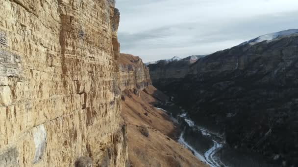 Vista aérea del movimiento a lo largo de la pared rocosa del cañón en la garganta en el Cáucaso. Muy cerca de la roca en invierno cuando hay poca nieve. 4k — Vídeos de Stock