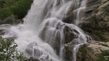 Yavaş çekim su büyük bir kayadan düşer. Bulutlu havalarda doğal ortamda şelale hafif yağmurlu