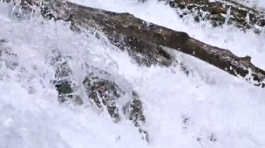 Yakın çekim taşlar ve izleme kablolama ile yavaş çekimde fırtınalı bir dağ nehri sprey. Küresel ısınma kavramı ve gezegendeki tatlı su miktarı sorunu