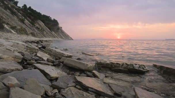 Close-up slow motion low wide angle small sea waves rolling on a rocky beach. Movement along the beach forward. Seaside. Evening sunset on a pebble rocky beach — Stock Video