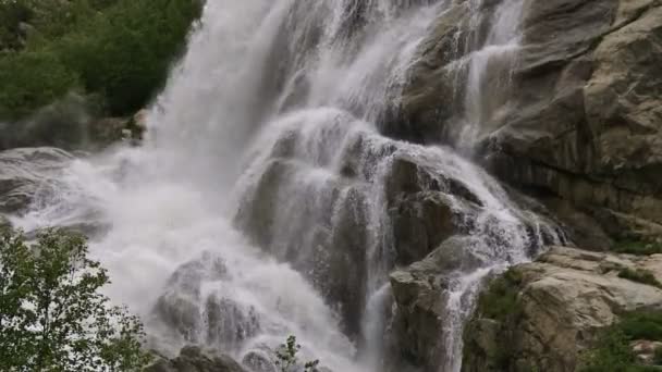 El agua en cámara lenta cae de una enorme roca. Cascada en el entorno natural en clima nublado con lluvia ligera — Vídeos de Stock