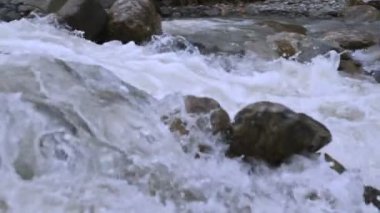 Yakın çekim taşlar ve izleme kablolama ile yavaş çekimde fırtınalı bir dağ nehri sprey. Küresel ısınma kavramı ve gezegendeki tatlı su miktarı sorunu