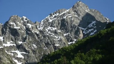 Yaz aylarında kar kalıntıları ile Kafkasya'nın yüksek kayalık dağlarının elleriyle yakın çekim Video panoraması