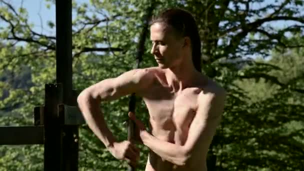 Medium close-up Morning training of a long-haired man for a fire show. Preparation for a performance without fire with torches and chains on a sunny summer morning in the outdoor — Stock Video