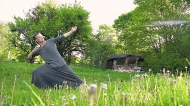 Genel plan Hint giysi ve pantolon Aladdin uygulamaları qigong genç bir adam eski bir kulübe 4k yanında yaz açık havada qi enerji ile çalışan egzersizleri yaparken