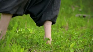 Çimenlerde pratik yapan bir adamın bacaklarının yakın çekim. Qigong egzersizleri çıplak ayak geçiş. Oryantal kültür 4k bir spor yaşam tarzı kavramı
