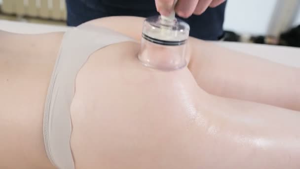Close-up de um massagista masculino fazendo massagem anti-celulite com uma lata de vácuo para uma menina paciente em um salão de spa profissional — Vídeo de Stock