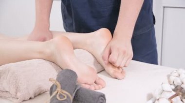 Yakın çekim bir erkek fizyoterapist bir güzellik ve sağlık spa genç bir kadına ayak ve topuklu ayak masajı yapıyor. Ayak ve vücut bakım konsepti