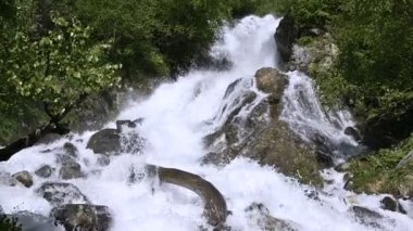 Yakın çekim taşlar ve izleme kablolama ile yavaş hareket yeşil bir ormanda fırtınalı bir dağ nehri sprey. Küresel ısınma kavramı ve gezegendeki tatlı su miktarı sorunu