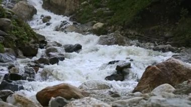 Yavaş çekim su büyük bir kayadan düşer. Bulutlu havalarda doğal ortamda şelale hafif yağmurlu