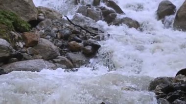 Yakın çekim taşlar ve izleme kablolama ile yavaş çekimde fırtınalı bir dağ nehri sprey. Küresel ısınma kavramı ve gezegendeki tatlı su miktarı sorunu