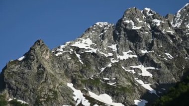 Yaz aylarında kar kalıntıları ile Kafkasya'nın yüksek kayalık dağlarının elleriyle yakın çekim Video panoraması
