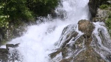 Yakın çekim taşlar ve izleme kablolama ile yavaş hareket yeşil bir ormanda fırtınalı bir dağ nehri sprey. Küresel ısınma kavramı ve gezegendeki tatlı su miktarı sorunu