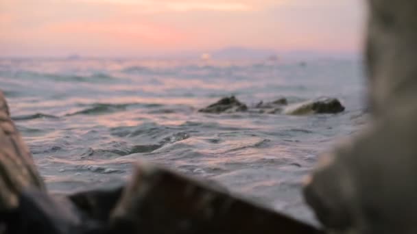 Primer plano cámara lenta ángulo bajo pequeñas olas marinas rodando en una playa rocosa. Junto al mar. Atardecer en una playa rocosa de guijarros — Vídeo de stock