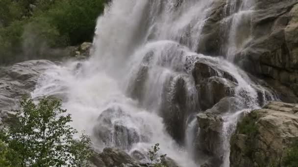 L'acqua al rallentatore cade da una roccia enorme. Cascata nell'ambiente naturale in tempo nuvoloso con pioggia leggera — Video Stock