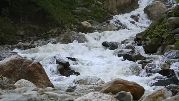 Água em câmara lenta cai de uma rocha enorme. Cachoeira no ambiente natural em tempo nublado com chuva leve — Vídeo de Stock