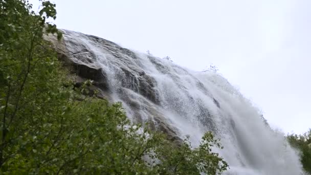 Closeup water drop and spray of a waterfall of a stormy mountain river in a green forest in slow motion with tracking wiring. The concept of global warming — Stock Video