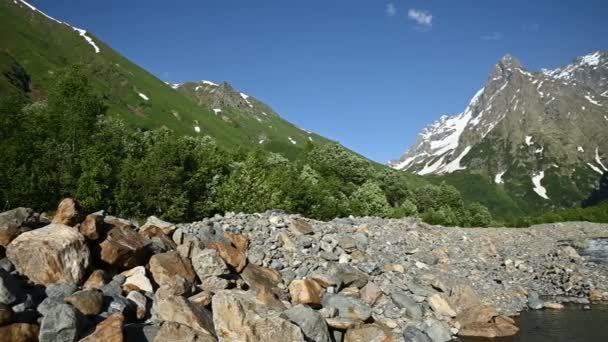 Panorama slow motion rocky shore of a stormy mountain river surrounded by woodlands and high rocky mountains of the Caucasus. Mountain landscape background — Stock Video