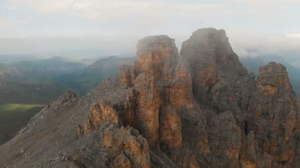 日没時に鋭い岩場の上空を飛ぶドローンの航空写真。極端な登山のための岩の形成の鋭い急な山。旅行ビデオ上のフライト — ストック動画