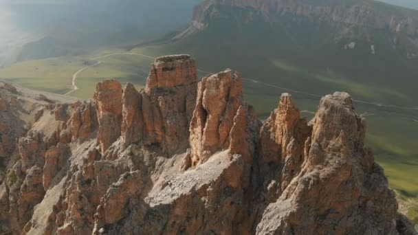 日没時に鋭い岩場の上空を飛ぶドローンの航空写真。極端な登山のための岩の形成の鋭い急な山。旅行ビデオ上のフライト — ストック動画
