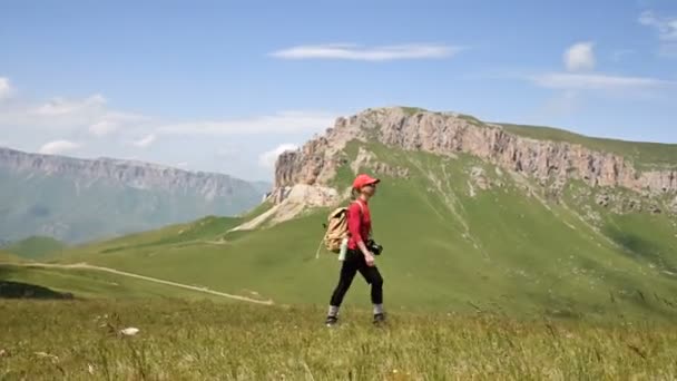 Girl fotograf går uppför backen mot bakgrund av klippor av en platå och himlen med moln. Koncept fototurer för landskaps fotografer — Stockvideo