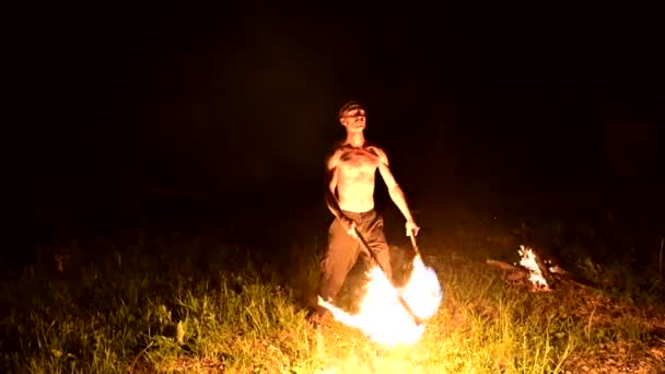 Slow Motion av en ung man i svarta byxor i totalt mörker visar en representation av en roterande brinnande ficklampa. Meditation i rörelse. Lugn och orubblill. Arbeta med eld. Lågmälen — Stockvideo