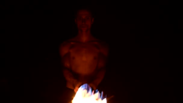 Närbild slow motion av en ung man i svarta byxor i totalt mörker visar en representation av en roterande brinnande ficklampa. Meditation i rörelse. Lugn och orubblill. Arbeta med eld. Lågmälen — Stockvideo