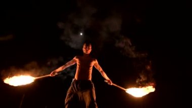 Siyah pantolon içinde çıplak gövde ile genç bir adamın yavaş hareket toplam karanlıkta dönen bir yanan meşale bir temsilgösterir. Meditasyon hareket halinde. Sakin ve sarsılmaz. Ateşle çalış. Düşük anahtar