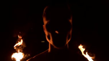 Siyah pantolonlu genç bir adamın karanlığa yakın yavaş hareketi, dönen yanan bir meşalenin temsilini gösterir. Meditasyon hareket halinde. Sakin ve sarsılmaz. Ateşle çalış. Düşük anahtar