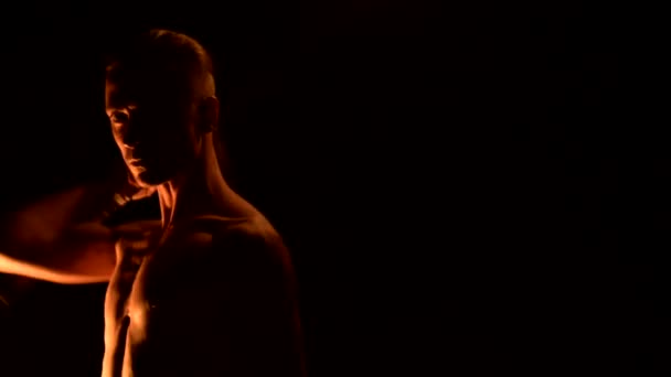 Close-up Slow Motion van een jonge man in zwarte broek in totale duisternis toont een representatie van een roterende brandende toorts. Meditatie in beweging. Kalm en onwrikbaar. Werken met vuur. Low Key — Stockvideo