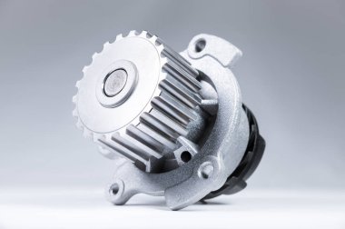 Bir degrade ile gri bir arka plan üzerinde bir motor su pompası soğutma için yeni metal otomobil pompası. Otomobil motoru için yeni yedek parça konsepti