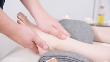 Yakın çekim bir erkek fizyoterapist bir güzellik ve sağlık spa genç bir kıza ayak masajı yapıyor. Ayak ve vücut bakım konsepti