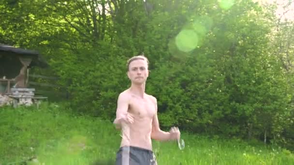 Medium shot en ung man med långt hår och en naken Torso är utbildad i kampsport och innan du talar med en personal eller lastrep i rotation utomhus på en sommarmorgon. Låg vinkel — Stockvideo