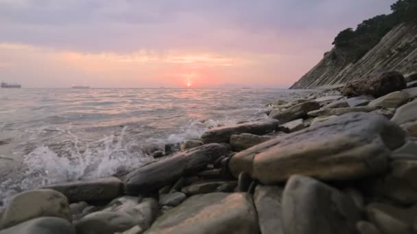 Närbild slow motion låg vidvinkel små havsvågor rullande på en stenig strand. Rörelse längs stranden framåt. Seaside. Kvälls solnedgång på en stenig klapperstensstrand — Stockvideo