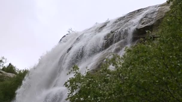 Gota de agua de primer plano y pulverización de una cascada de un río de montaña tormentoso en un bosque verde en cámara lenta con cableado de seguimiento. El concepto de calentamiento global — Vídeos de Stock