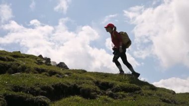 Kız fotoğrafçı güneşli bir günde bulutlar ile arka plan ve gökyüzü üzerinde yokuş yukarı gider. Manzara fotoğrafçıları için konsept fotoğraf turları. Dağ yürüyüşü