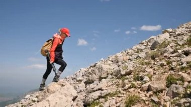 Kız fotoğrafçı güneşli bir günde bulutlar ile arka plan ve gökyüzü üzerinde yokuş yukarı gider. Manzara fotoğrafçıları için konsept fotoğraf turları. Dağ yürüyüşü