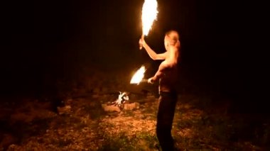Siyah pantolonlu genç bir adamın karanlıkta yavaş hareketi, dönen yanan bir meşalenin temsilini gösterir. Meditasyon hareket halinde. Sakin ve sarsılmaz. Ateşle çalış. Düşük anahtar